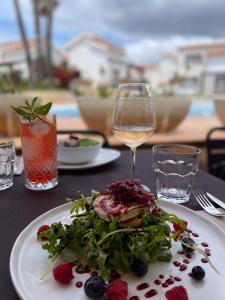 卡兰博希Nuramar Resort & Villas的一张桌子,上面放着一盘食物和一杯葡萄酒