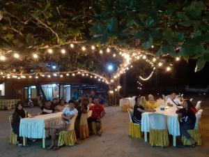 PasarbaruNew Belitung Holiday Resort的一群坐在桌子旁的灯光下的人