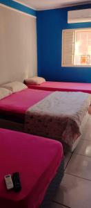 奥林匹亚Casa em Olimpia 2的客房设有两张带粉色床单的床和遥控器