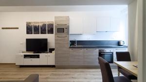 马累Relais Gentilini的厨房配有白色橱柜和桌椅