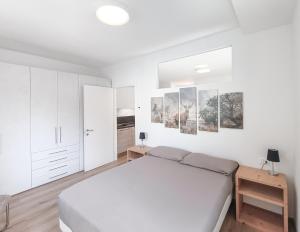 马累Relais Gentilini的一间白色的卧室,配有一张床和墙上的一些照片