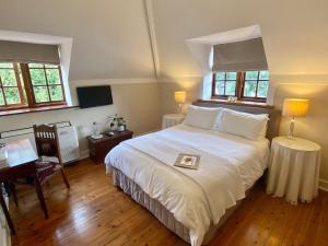 开普敦阿考恩楼旅馆的卧室配有一张白色大床和一张书桌