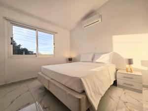 帕福斯2BD Garden Apartment的白色的卧室设有一张大床和一个窗户