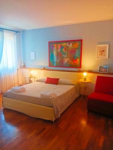 下卡斯泰卢乔La quercia di Massena的一间卧室配有一张大床和一张红色椅子