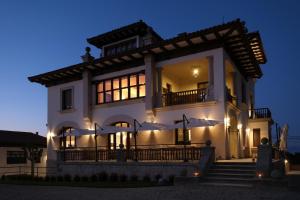 库迪列罗Hotel El Rosal de Cudillero的夜晚有灯的大白色房子