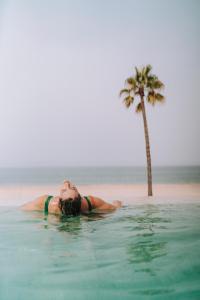 加的斯Cádiz Bahía by QHotels的躺在棕榈树旁边的水里的妇女
