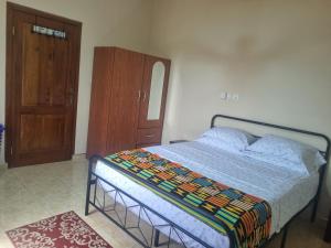 阿克拉Cozy Escape in Accra by Manna Hospital的一间卧室配有一张床和一个木制橱柜