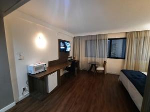 圣保罗Flat Hotel Internacional Ibirapuera 2534的酒店客房配有一张床、一张书桌和一台电视。