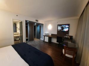 圣保罗Flat Hotel Internacional Ibirapuera 2534的酒店客房配有一张床、一张书桌和一台电视。