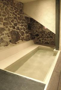 吉霍－德圣巴巴拉El jazmín de la Fuente casa rural的石墙客房内的浴缸