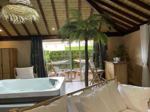 CouperdrixLa Ferme Briarde的一间带浴缸和棕榈树的客厅