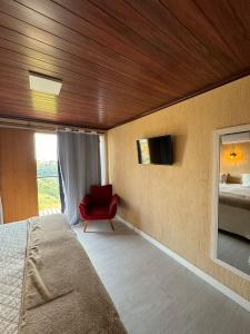 帕蒂杜阿尔费里斯Pousada Recanto Querubins的一间卧室配有一张床和一张红色椅子