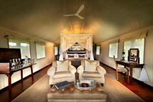 阿多戈拉大象营酒店的一间卧室配有一张床、一张沙发和椅子