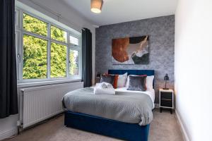 Bramcote4 Bedroom House in Bramcote, with Driveway for 2 Cars的一间卧室设有蓝色的床和2个窗户。