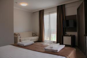 居吕克Gulluk Life Hotel的一间卧室配有一张床、一张沙发和一个窗口