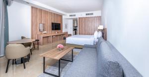 迪拜Pyramisa Hotel Apartments的酒店客房配有床、沙发和桌子。
