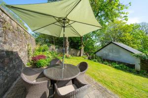 邓迪Binrock Lodge的花园里的桌子和遮阳伞