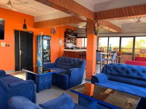 瓦加杜古AG HOTEL Ouaga的客厅设有蓝色的沙发和橙色的墙壁。
