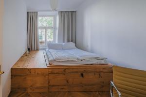 布拉格Art hotel Sazavska的窗户间木制平台上的一张床位