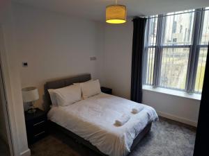 赫尔Suffolk House Apartments HU1的一间卧室配有一张带白色床单的床和一扇窗户。