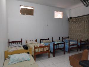 平达莫尼扬加巴POUSADA PERLLA's Pindamonhangaba的一间设有一组床、椅子和一张桌子的房间