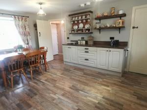 邓吉文Christie's Cottage的厨房配有白色橱柜和桌椅