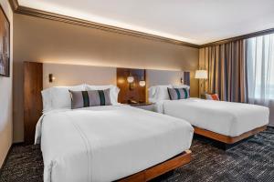 奥斯汀奥斯汀市中心欧尼酒店的配有白色床单的酒店客房内的两张床