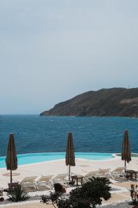 凯勒里瓦迪米科诺斯潘泰恩公寓酒店的一个带椅子和遮阳伞的游泳池以及大海