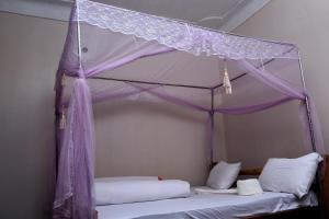 KapchorwaSipi Guest House的卧室配有带白色床单的天蓬床