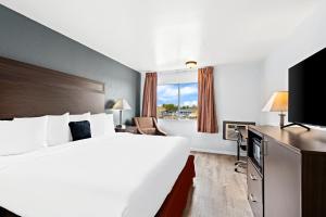 亚基马Red Lion Inn & Suites Yakima的酒店客房设有一张大床和一台电视。