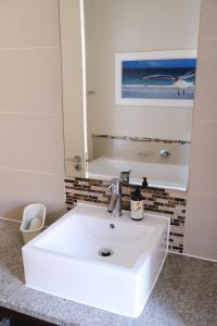 西蒙镇Penguin Paradise Apartment Simons Town的浴室设有白色水槽和镜子