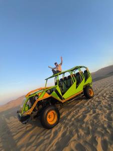 帕拉卡斯HOSPEDAJE WELCOME paracas的两个人站在沙漠绿色吉普车顶上