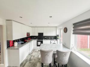 雷纳姆Beautiful Newly Renovated House in Rainham Essex的厨房配有白色橱柜和桌椅