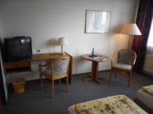 奥尔登堡Stadthotel Oldenburg的酒店客房配有带电视和椅子的书桌