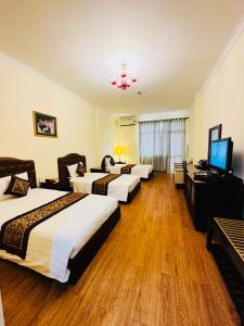 胡志明市Ngọc Lan Hotel的一间酒店客房,设有三张床和一台平面电视