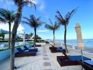 头顿Lfamily Ocean view Apartment 91m2 - ARIA Vung Tau Private Beach Resort, căn hộ Aria Vũng Tàu 91 m2 view biển, bãi biển riêng的棕榈树海滩上的一排长椅