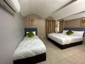 吉隆坡SS Grey Hotel的一间卧室配有两张带绿色枕头的床