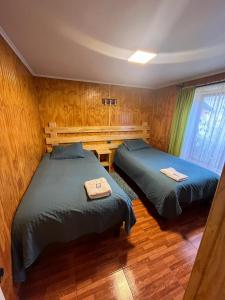 科伊艾科Apart Hotel Español Coyhaique的木墙客房的两张床
