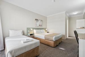 阿德莱德Glenelg Dockside Motel的酒店客房设有两张床和一张桌子。