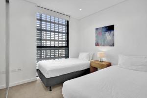 悉尼Stunning Apartment ATC10610的一间卧室设有两张床和窗户。