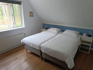 洛赫姆Bosvilla Lochem的卧室设有一张白色大床和一扇窗户。