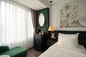 河内Paradise Suites Truc Bach lake的一间卧室配有一张床和一张绿色沙发
