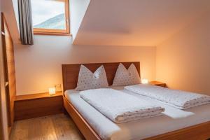 纳兹-夏韦斯Huberhof的一间卧室配有一张带白色床单的床和一扇窗户。
