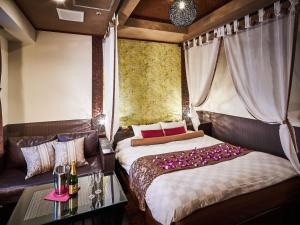 千叶BaliAn Resort Chiba-Chuo的一间卧室配有一张床、一张沙发和一张桌子
