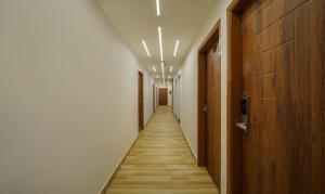 古瓦哈提Treebo Trend Park Palace的走廊设有长长的走廊,铺有木地板,配有灯