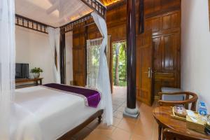 富国Maison Du VietNam Resort & Spa的卧室配有白色的床、桌子和桌子