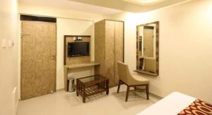 孟买Hotel Golden Park Near NESCO的酒店客房配有一张床、一把椅子和一台电视。