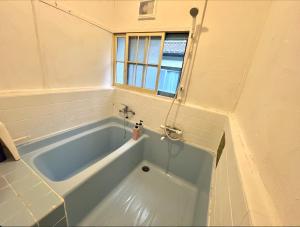汤河原町温泉街の入り口にあるゲストハウス SLOW HOUSE yugawara的带窗户的浴室内的蓝色浴缸