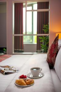 布兰察斯镇布兰查斯镇卡尔顿酒店的床上的托盘,上面放着咖啡和糕点