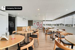 班加罗尔Super Townhouse Ulsoor Near Halasuru Metro Station的餐厅设有木桌、椅子和窗户。